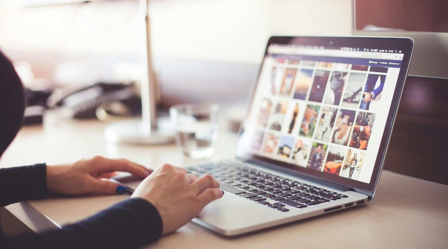 Close-up of hands typing on a laptop with an image gallery open on the screen.